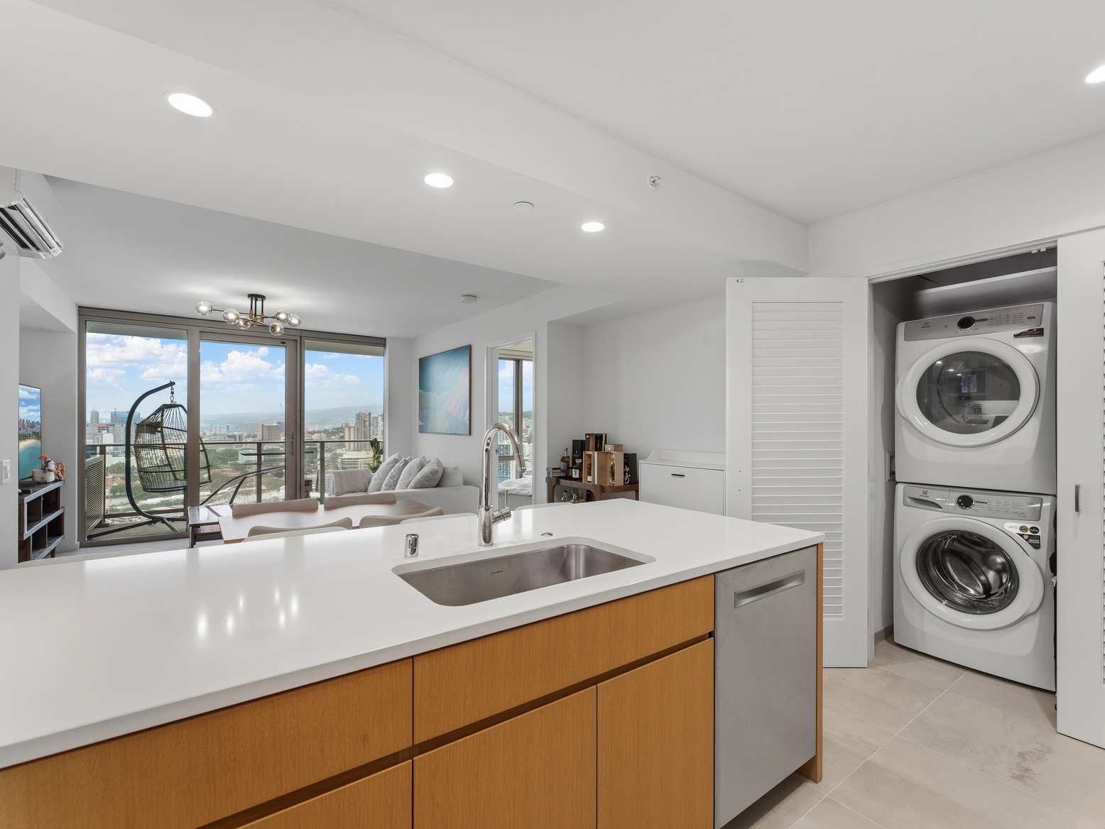 Kitchen island with sink beside the stacked washer and dryer, looking to the living room