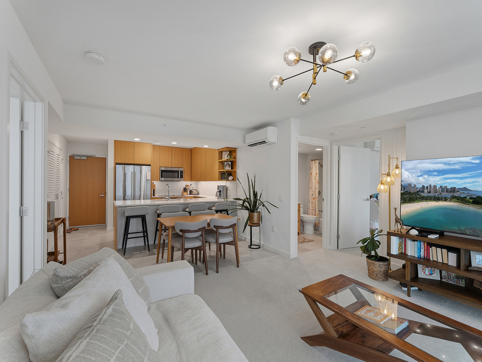 Living room with dining table, kitchen beyond, and hallway to the bedrooms