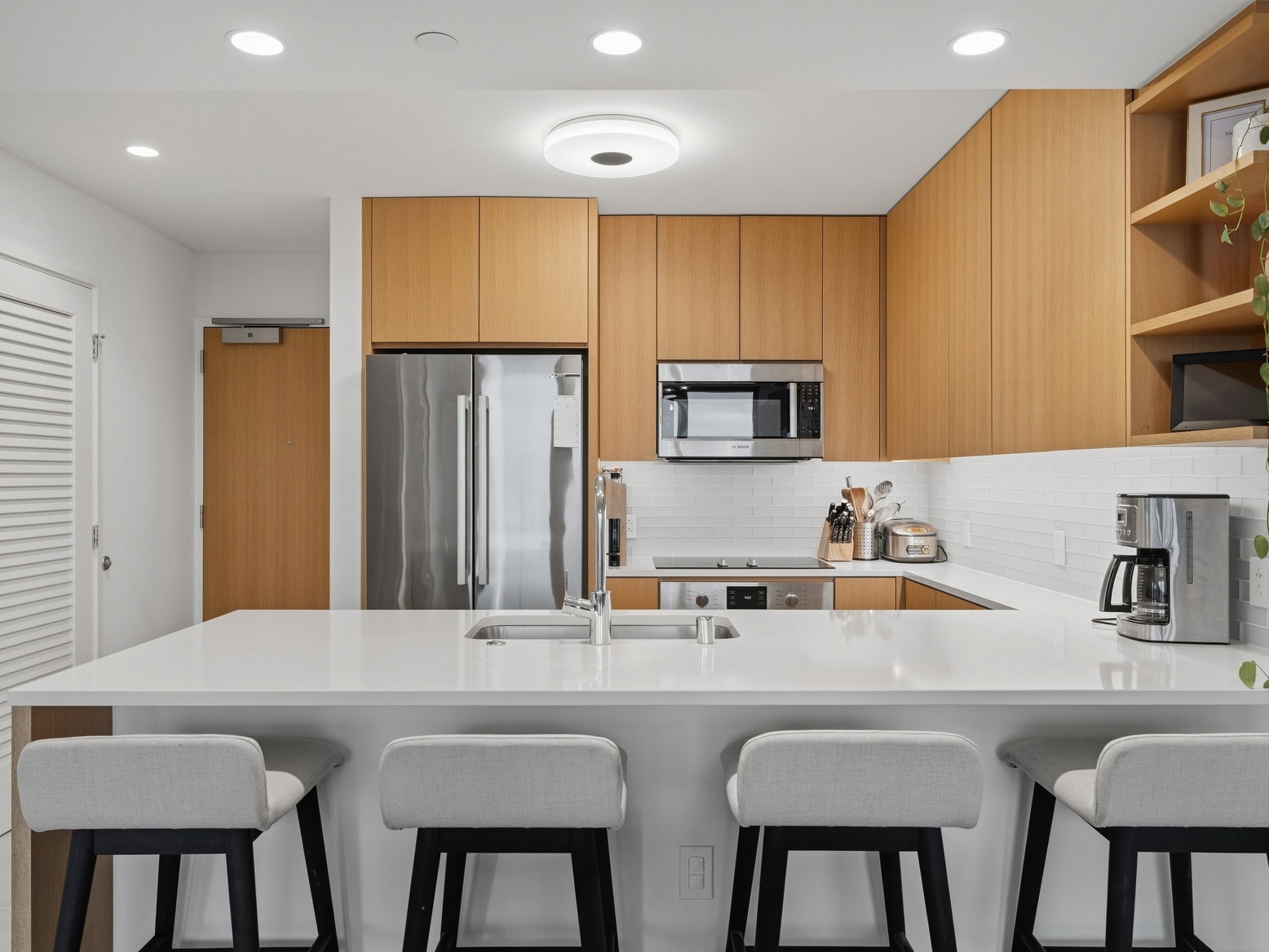 Kitchen island with sink and bar stools in front of the appliance wall