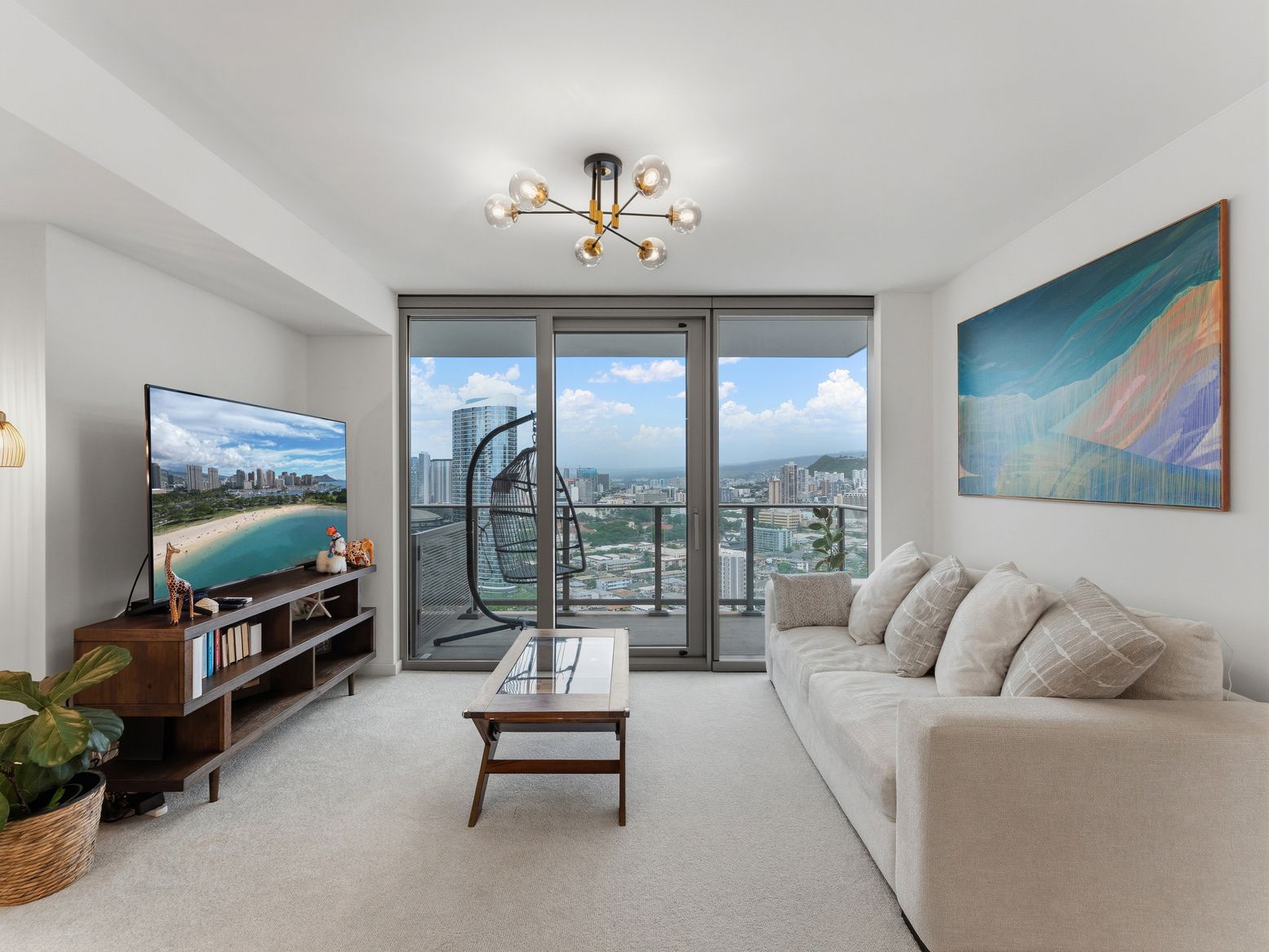 Living room seating beneath a large coastal artwork with city views