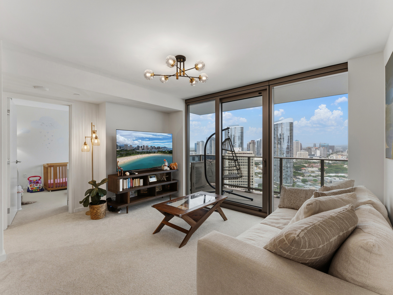 Living room with sofa, TV console, and balcony swing chair overlooking the city